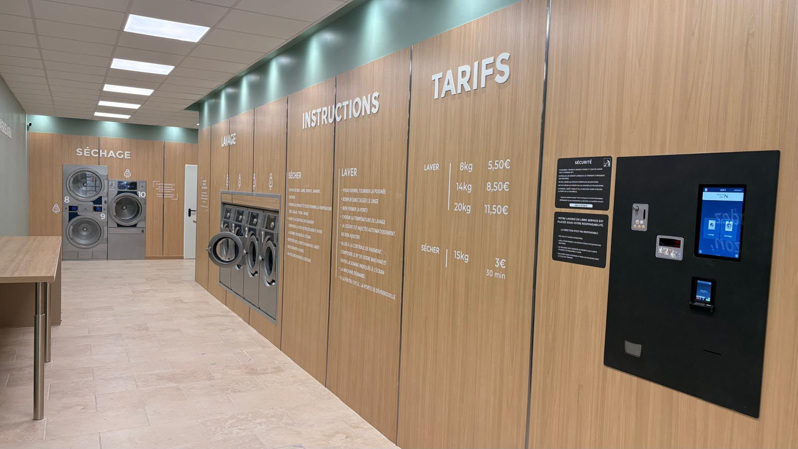 Intérieur de la laverie La Réal à Perpignan, murs vert sauge, machines et habillage en bois